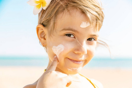 海滩上的孩子涂抹防晒霜。 选择性聚焦。 人民。