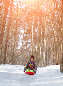 快乐的年轻女孩在冬季公园里雪橇