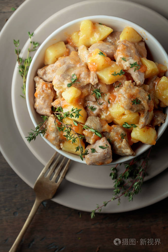 用土豆胡萝卜和香料在木制背景上炖的肉爱尔兰炖菜撒上绿色百里香上面