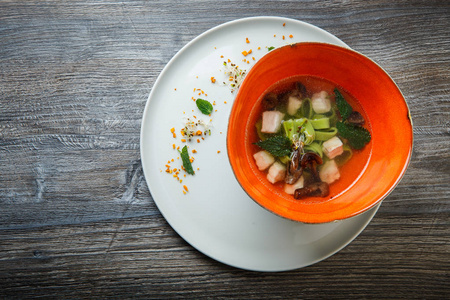 顶部观看美味的面条汤与蘑菇，肉和荨麻叶提供在深餐厅碗木桌。