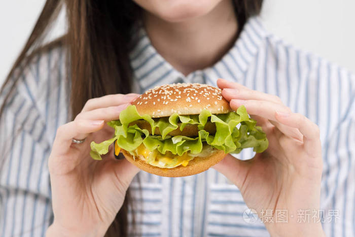 苗条的黑发女孩手里拿着一个汉堡包.