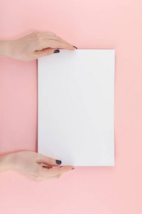 创意平躺顶部的女人手黑色指甲与空的A4纸页模拟在粘贴千禧粉纸背景复制空间。最小的文字写作概念模板的文字书写博客