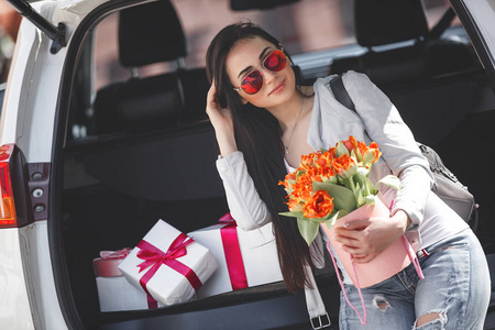 春天美丽的女士,带着一束郁金香汽车里的女人照片