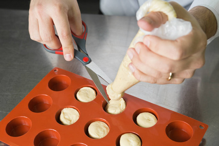 黄油油性糕点面团通过烘烤管道挤压成圆形模具，准备在烤箱中烘焙。