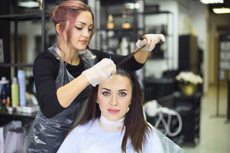 专业的女理发师在设计美发于设计美发沙龙的女性客户，使她的头发染色。 染发剂染色工艺
