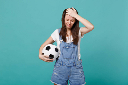 脾气暴躁的女球迷支持最喜欢的球队与足球，手放在额头上孤立在蓝色绿松石背景。 人们情感运动家庭休闲观念。 模拟复制空间