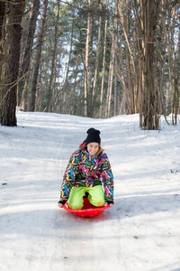 快乐的年轻女孩在冬季公园里雪橇