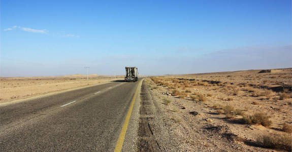 卡车在约旦的沙漠中行驶, 山谷中的柏油路上有电线杆, 日出后清晨在荒野中行驶