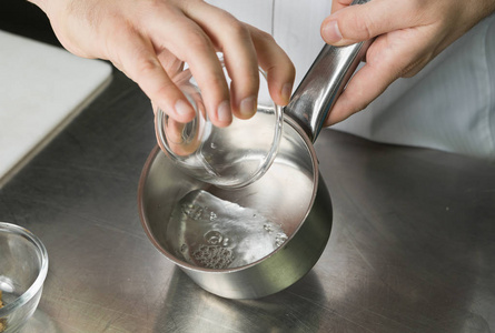 清糖糖浆被倒入一个银色的烹饪锅，准备混合成一个甜的食谱。