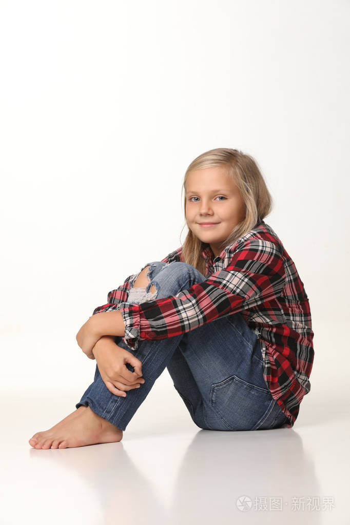 可爱的女孩坐在地板上真诚地微笑白色背景