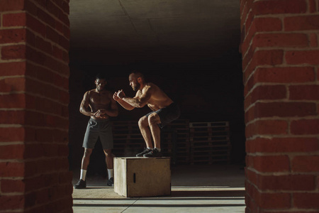 肌肉多民族运动的朋友做盒子跳跃, 而在健身房锻炼