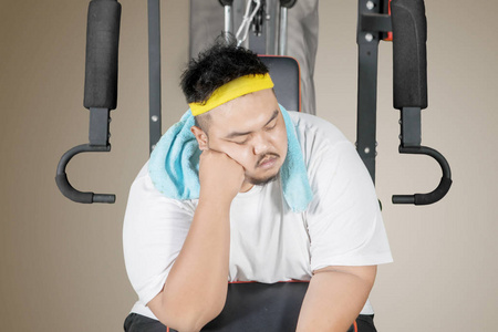 年轻胖子坐在健身机上睡着的画面