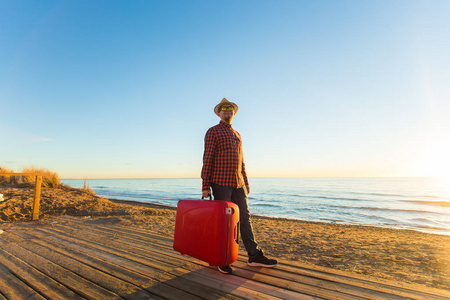 海, 旅行, 人的概念一个人站在海边与红色手提箱