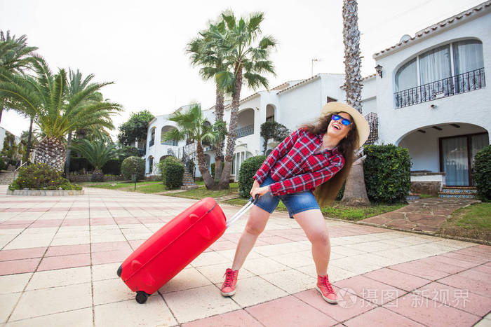 旅行度假和人的概念有趣的女人拉着她沉重的行李箱微笑着