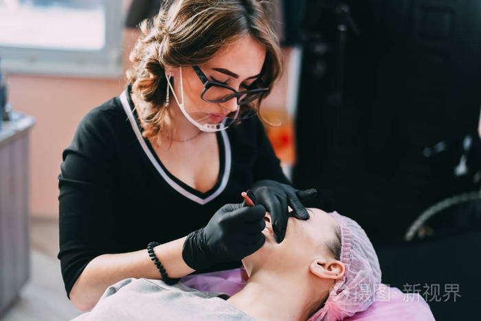 永久弥补美容院美女的红唇. 特写美容师做纹身嘴唇.