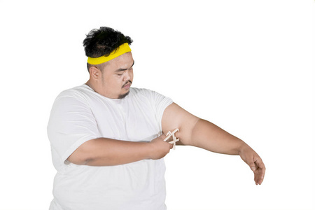 一位亚洲胖子用白色背景的卡钳测量手臂脂肪层的照片