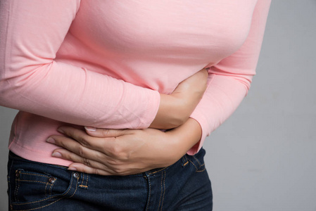 年轻的女人胃痛得很痛。 慢性胃炎。 腹部膨胀和保健概念。