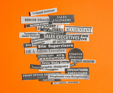 工作或职业概念在橙色背景下从报纸上剪下的多个职称或职业
