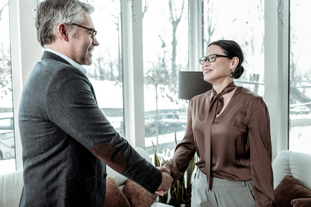 黑头发优雅的女人在灰色的裤子微笑对她的生意伙伴照片