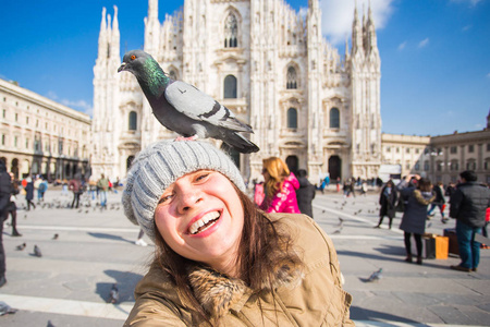 意大利, 游览和旅行概念年轻的有趣的女人采取自拍与鸽子在米兰大教堂前