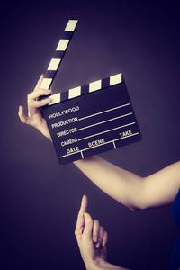 女人拿着专业的电影板岩电影拍板。 好莱坞制作对象概念。 演播室拍摄的黑色背景。