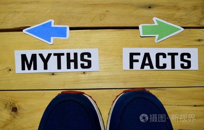 神话或事实相反的方向标志与运动鞋在木制复古背景.