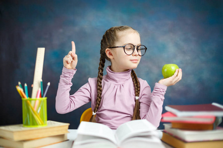 漂亮的小学生女孩得到想法做家庭作业。 快乐聪明的小学习者带辫子思考问题坐桌子。 学校活动阅读课本教育系统概念特写照片