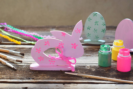 制作复活节装饰复活节彩蛋和兔子。 画笔和水粉的绘画和着色木制玩具。 创造性的过程。 儿童DIY概念