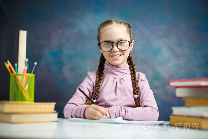 漂亮聪明的眼镜新手坐在文具桌上拍照