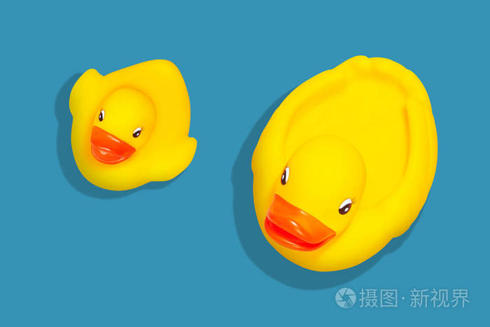 又大又小的玩具鸭子在蓝色的背景上设置了阴影从阿伯看