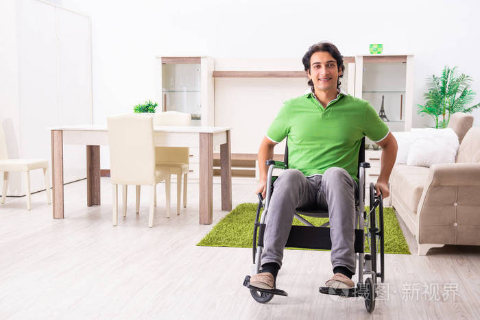 年轻的英俊男子在轮椅在家里