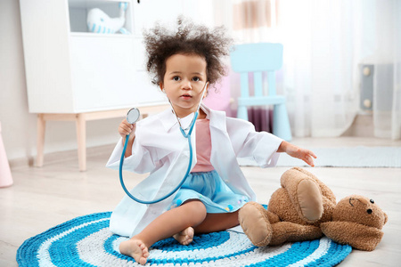 可爱的非裔美国人孩子在家玩听诊器和玩具兔子时想象自己是医生