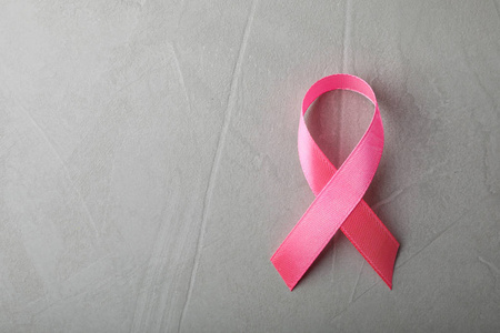 粉红色丝带在灰色背景顶部视图与空间的文本。 乳腺癌意识概念