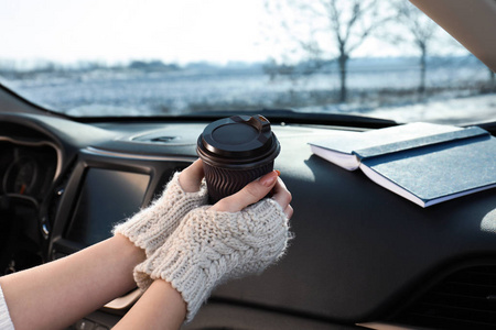 年轻女子戴着温暖的手套拿着一杯咖啡，特写镜头。舒适的气氛