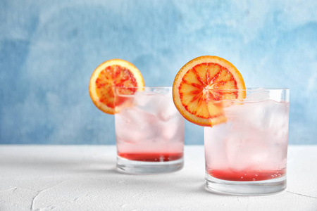 杯子的饮料与冰块和橙色在桌子上的颜色背景。文本空间