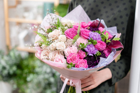 颜色的。美丽的新鲜切花混合鲜花在女人的手。花店的花商的作品。精致的柔和色调颜色