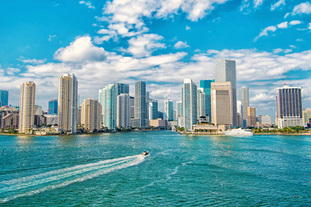 迈阿密与蓝色多云的天空，白色的船航行在迈阿密市中心的摩天大楼的鸟瞰图