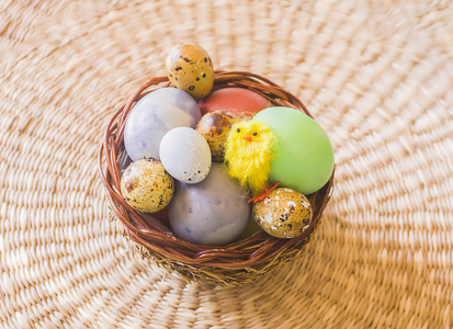 五颜六色的复活节彩蛋和装饰小黄鸡玩具在柳条篮子。
