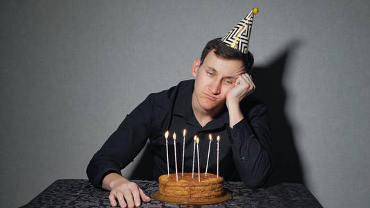 一个人庆祝一个假期, 他独自坐在一张桌子上, 一个蛋糕和一支蜡烛