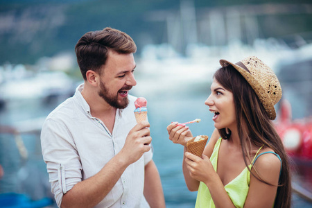 快乐的一对夫妇在假期里约会和吃冰淇淋。 海洋背景。