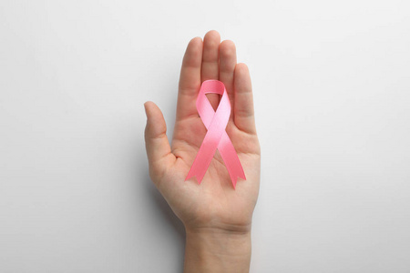女人拿着粉红色的丝带在白色背景的顶部视图。 乳腺癌意识概念