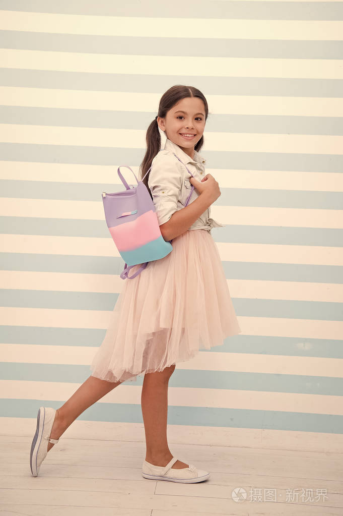 小女孩可爱的笑脸背着书包扛着孩子长卷曲的头发穿时髦的衣服