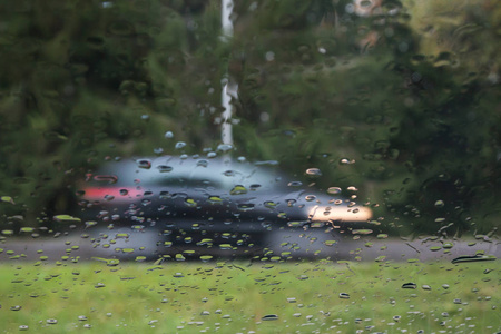 雨滴在汽车玻璃上，焦点在雨滴上。 观看街道和汽车的运动。 长曝光照片