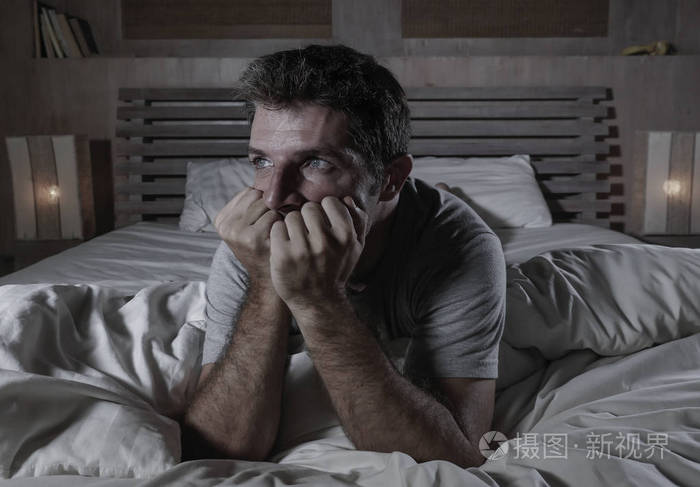 躺在床上的年轻迷人悲伤和沮丧的男人的戏剧性肖像感到焦虑抑郁焦虑