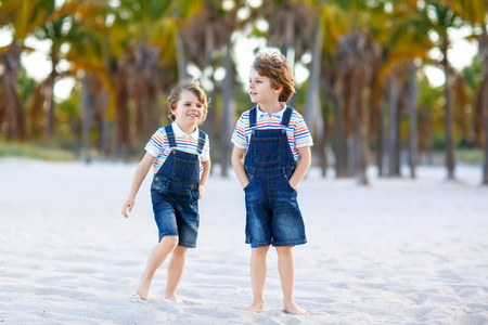 兄弟姐妹兄弟,在家庭中两个双胞胎与棕榈树在背景上.