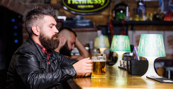 希普斯特在酒吧放松。男胡子的人坐在酒吧的酒吧柜台里。留胡子的人在黑暗的酒吧里悠闲地度过。残酷的嬉皮士放松。周末的生活方式。酒吧的