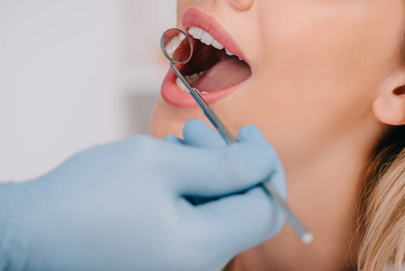 牙科医生用口镜检查年轻妇女牙齿的局部观察