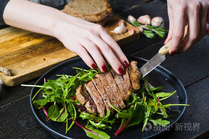 s hands prepare a salad with beef tenderloin and arugula. Side v