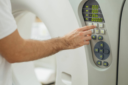 医疗技师的手按压ct扫描仪上的按钮。