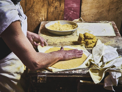 一个厨师在木制的乡村桌子上做玉米饼。